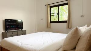 a bedroom with a white bed and a television at Zen Trinity House in Ko Phangan