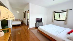 a white bedroom with a bed and a television at Zen Trinity House in Ko Phangan