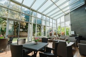 a conservatory with tables and chairs and windows at Hotel For You in Cernusco sul Naviglio