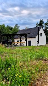 a white house with a picnic table in a field at House by the water in Lesík
