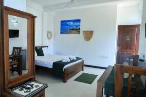 a bedroom with a bed and a table and a mirror at Kyo Garden Villa in Negombo