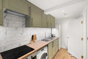 a kitchen with green cabinets and a washer and dryer at Chic & Modern Beckenham Retreat in Beckenham