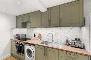 a kitchen with green cabinets and a sink at Chic & Modern Beckenham Retreat in Beckenham +10 photos