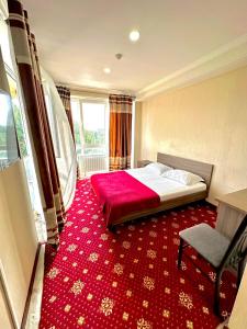 a bedroom with a bed and a red carpet at Harmony Inn in Almaty