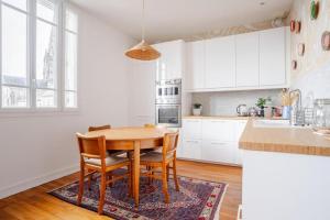 a kitchen with white cabinets and a wooden table and chairs at Chambre chez l'habitant - Arty & Élégante - SDB privée in Nantes +25 photos