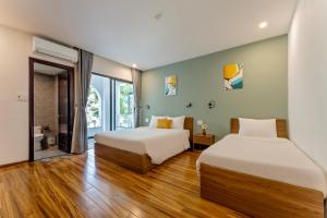two beds in a room with wooden floors at Buddy January Villa in Hoi An +29 photos
