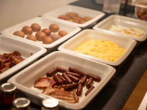a table topped with trays of food with eggs and sausage at The Classic Hotel Nicosia - Handwritten Collection in Nicosia