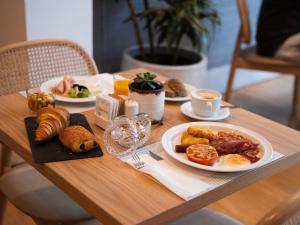 a wooden table with plates of breakfast food on it at The Classic Hotel Nicosia - Handwritten Collection in Nicosia