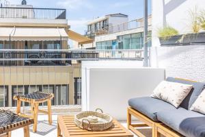 a patio with a couch and tables on a balcony at Ernest Suites Monastiraki in Athens