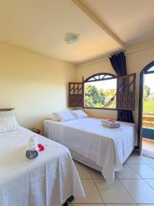 a bedroom with two beds with white sheets and a window at Casa Magna in Itacaré