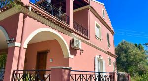 a pink building with a balcony on the side at Villa Valia Seaside in Ipsos