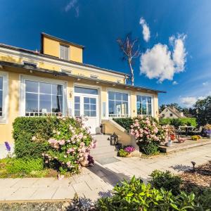 a yellow house with flowers in front of it at Boutique Hotel Villa Wahnfried Thiessow in Thiessow