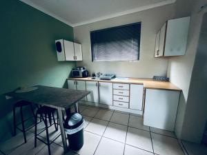 a small kitchen with white cabinets and a table at Marikal Guesthouse in Upington +11 photos