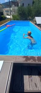 a boy in a swimming pool with a frisbee at Sky Apartments Petrovac in Petrovac na Moru