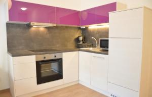 ブダペストにあるTwo Bedroom Apartment at Bajcsyの白いキャビネットと紫のアクセントが施されたキッチン