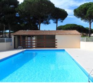 a swimming pool in front of a small building at Les Cigalines très proche village natu in Cap d'Agde