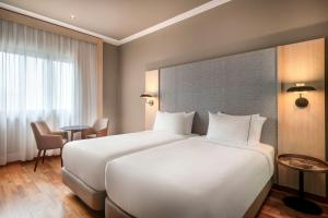 ein Hotelzimmer mit zwei Betten und einem Tisch in der Unterkunft AC Hotel A Coruña by Marriott in A Coruña