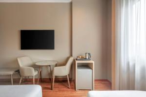 ein Wohnzimmer mit Tisch, Stühlen und Fernseher in der Unterkunft AC Hotel A Coruña by Marriott in A Coruña