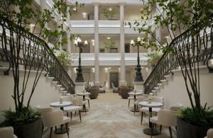 a lobby with tables and chairs and stairs at Badischer Hof Baden-Baden - Leonardo Limited Edition in Baden-Baden