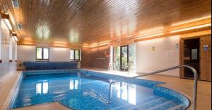 a swimming pool in a house with a wooden ceiling at Lake View - Old Mill Cottages in Ilfracombe