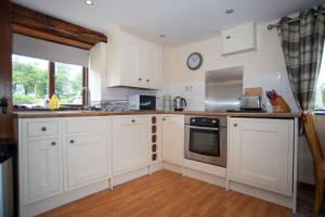 a kitchen with white cabinets and a clock on the wall at Lake View - Old Mill Cottages in Ilfracombe