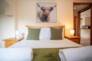 a bedroom with a bed with a bull picture on the wall at Lake View - Old Mill Cottages in Ilfracombe +14 photos
