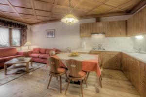 a kitchen and living room with a table and a couch at Residence Dolomieu in San Cassiano +14 photos