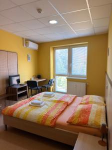 a bedroom with a bed and a desk with chairs at Penzion VV SUN - REOS in Hodonín
