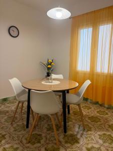 a dining room table with white chairs and a vase of flowers at Apartment Nela in Brna +18 photos
