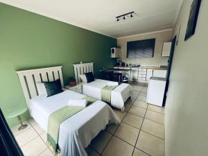 two beds in a room with green walls at Marikal Guesthouse in Upington