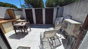 a patio with chairs and a heater and a table at Les Cigalines très proche village natu in Cap d'Agde