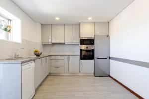 a white kitchen with white cabinets and appliances at Bright & Spacious Flat with Balcony by HostWise in São Mamede de Infesta