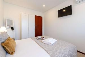 a bedroom with a white bed with a towel on it at Bright & Spacious Flat with Balcony by HostWise in São Mamede de Infesta +56 photos