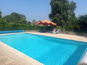 a swimming pool with an umbrella and two lawn chairs at Sleeps10-PrivatePool-GamesRoom-GatedGardens in Paizay-le-Chapt