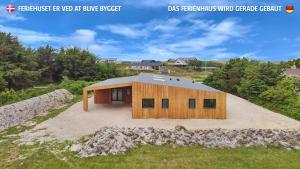 a house that is on top of a field at Eksklusivt Luksusferiehus Med Pool Sj455 in Harboør