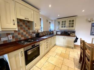 a kitchen with white cabinets and a stove top oven at Hollow Brook grown ups escape peace and quiet in Eyam +86 photos