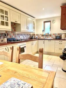 a kitchen with white cabinets and a wooden table at Pretty Wood Cottage Quiet Cottage in Private Meadow in Eyam