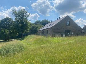 an old barn sitting in a field of grass at Riley Wood Cottage Peaceful Cottage, Views & Walks in Eyam