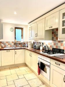 a kitchen with white cabinets and a stove top oven at Riley Wood Cottage Peaceful Cottage, Views & Walks in Eyam