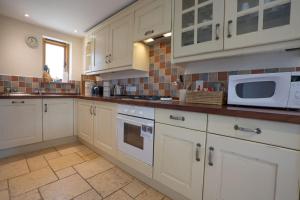 a kitchen with white cabinets and a microwave at Riley Wood Cottage Peaceful Cottage, Views & Walks in Eyam