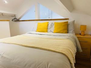 a bedroom with a large bed with yellow pillows at Barn Peaceful Stay with Far-Reaching Views in Eyam