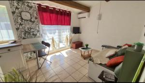a living room with a couch and a table and a window at Les Cigalines très proche village natu in Cap d'Agde