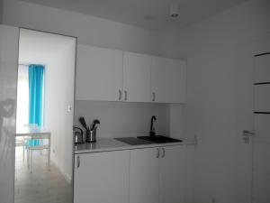 a white kitchen with white cabinets and a sink at Wisełka Apartamenty Sea & Lake in Wisełka