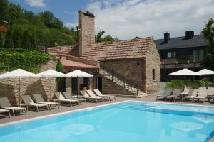 a swimming pool with chairs and umbrellas next to a building at Камінь in Ostrovets