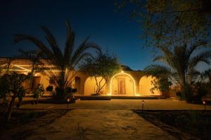 a house with a courtyard at night with palm trees at Ayur Lodge Siwa Oasis in Siwa