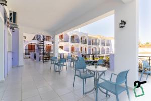 a patio with blue chairs and tables and a building at Hotiday Zakynthos Argassi in Zakynthos