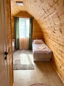 a room with two beds in a wooden room at Beshik Guest House in Bokonbayevo
