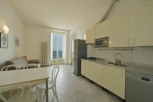 a kitchen with white cabinets and a table and chairs at Hotel La Balnearia in Alassio
