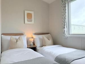 two beds in a small room with a window at Coastal Escape in Heysham