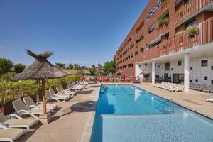 a swimming pool with chairs and an umbrella and a hotel at Résidence Odalys Terra Gaia in Sète